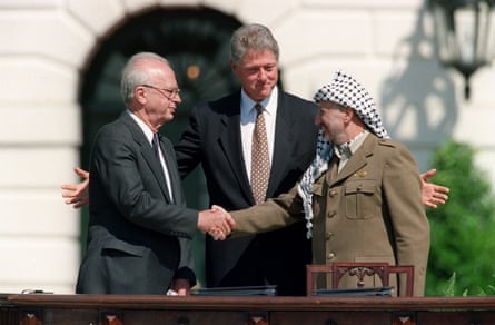 A smiling man stands in the middle of two other men shaking hands
