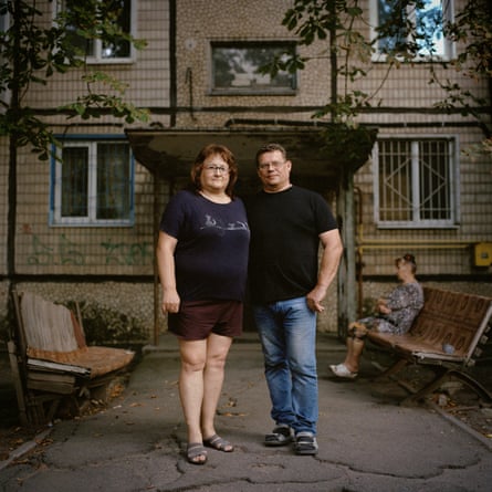 A man and woman stand next to each other in front of a residential block.