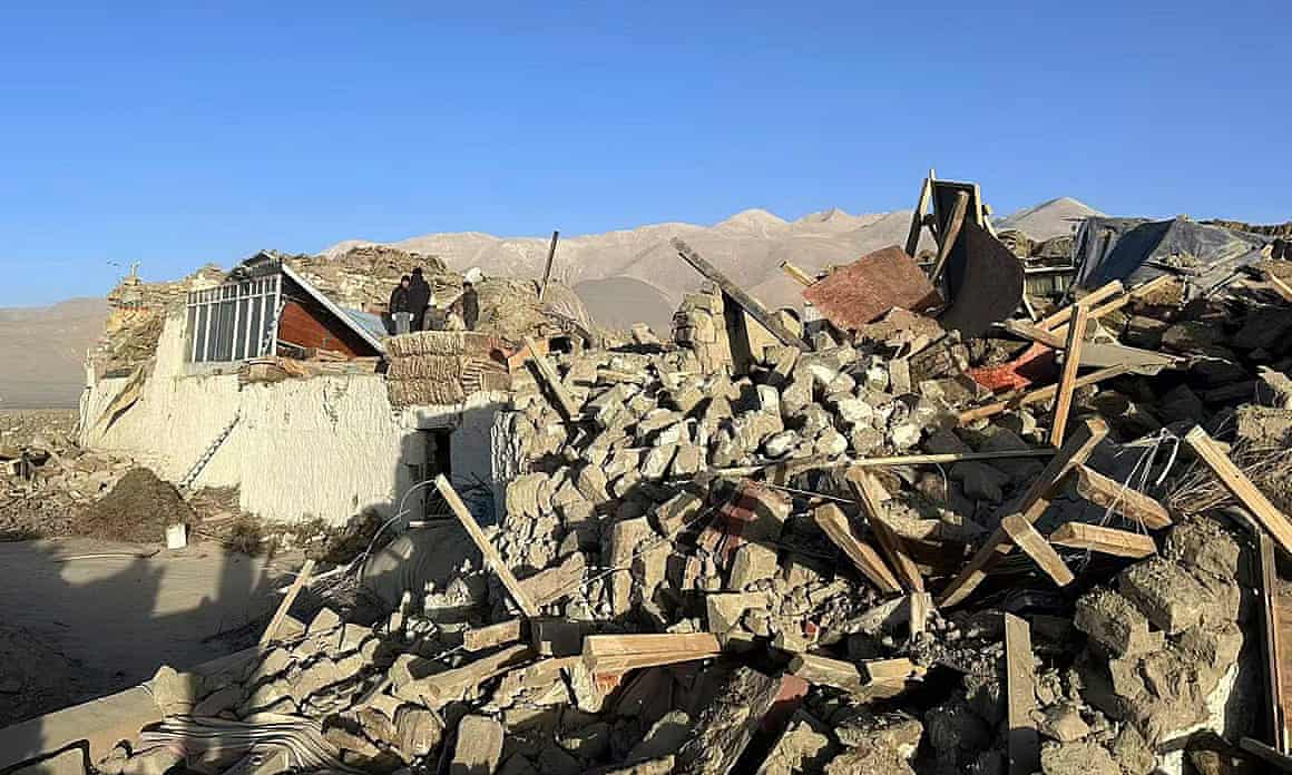 People stand amid damaged houses in the aftermath of an earthquake in Tonglai Village.