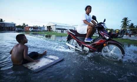 A woman rides her scooter through floodwaters occurring around high tide in a low lying area near the airport on November 27, 2019 in Funafuti, Tuvalu. Sea water sometimes percolates up through the porous coral land in the area during high tides. The low-lying South Pacific island nation of about 11,000 people has been classified as extremely vulnerable to climate change by the United Nations Development Programme. 