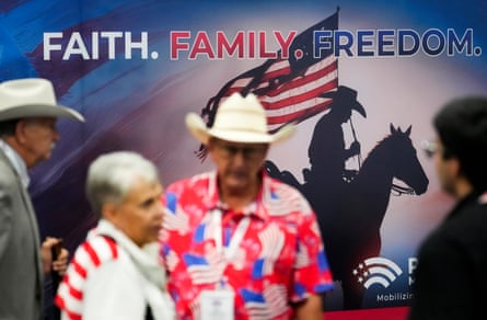 people stand near a display that shows a silhouette of a person on a horse holding a US flag under the words ‘faith family freedom’
