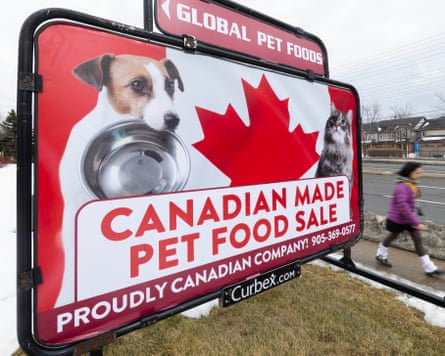 A woman walks past a billboard advertising a ‘Canadian-made pet food sale’