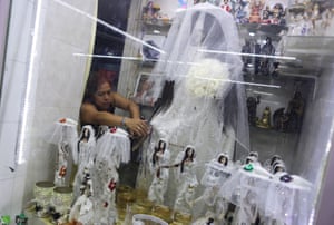 A woman fixes the dress of a Santa Muerte statue in her shrine