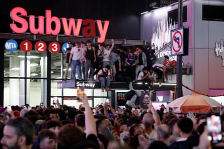 New York Knicks fans stand on a subway entrance canopy as they celebrate Friday’s win.