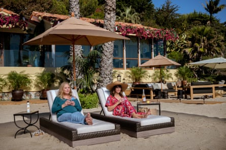 Actors Christina Applegate and Linda Cardellini sitting on loungers on a beach, on set for Dead to Me, 2021