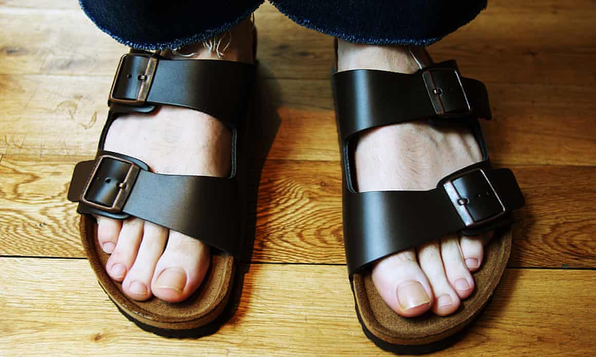 Feet wearing a pair of black Arizona-style Birkenstocks.
