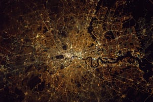 London at nightThe River Thames flows through the centre, with many of London’s famous bridges visible. The distinctive Isle of Dogs and Thames Barrier can also be seen. The central dark regions mark London’s royal parks, with Richmond Park lower left.