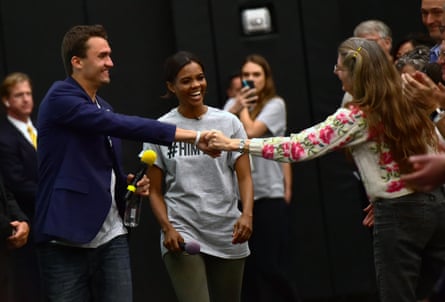Charlie Kirk shakes the hand of a woman as Candace Owens smiles at her