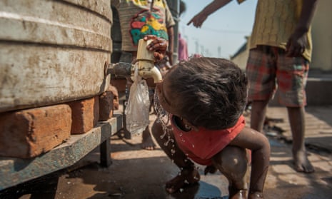 A boy drinks from the tap of a water tank outside a night shelter in New Delhi, India. 