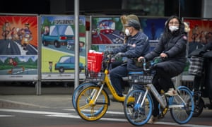 Bicyclists wearing face masks to protect against Covid-19 wait at an intersection in Beijing on 23 December as China orders a lockdown of as many as 13 million people in the northern city of Xi’an.