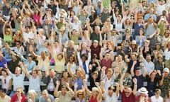 A stadium crowd cheering, arms and hands raised in celebration