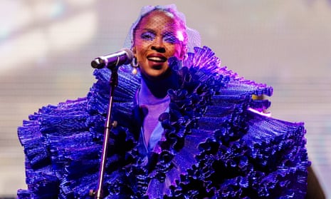 Lauryn Hill in a ruffled blue/purple outfit in front of a microphone
