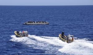 Migrants sit in their boat during a rescue operation by Italian navy vessels off the coast of Sicily.