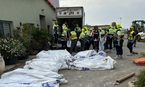 Rescue workers remove body bags from the Alumim kibbutz