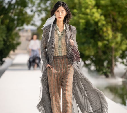 Model wearing a checked shirt, striped trousers and long billowy coat.