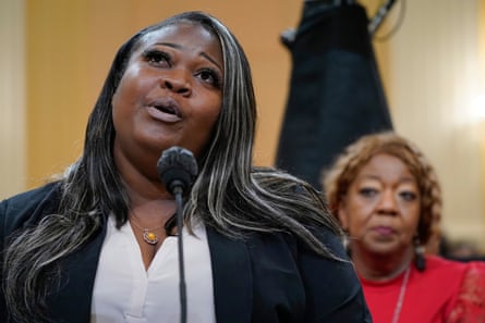 A woman speaks into a microphone standing behind another woman