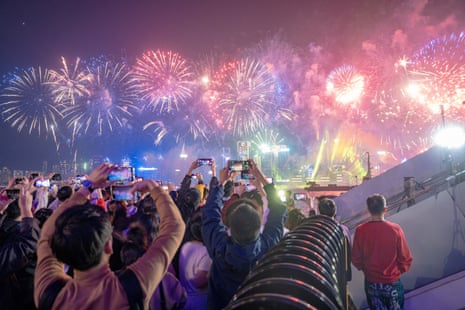 People take photographs with their phones of the fireworks over Victoria Harbour in Hong Kong.