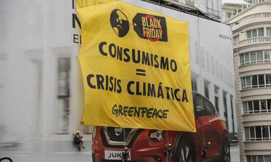 A banner denouncing consumerism is unfurled during a climate protest in Madrid