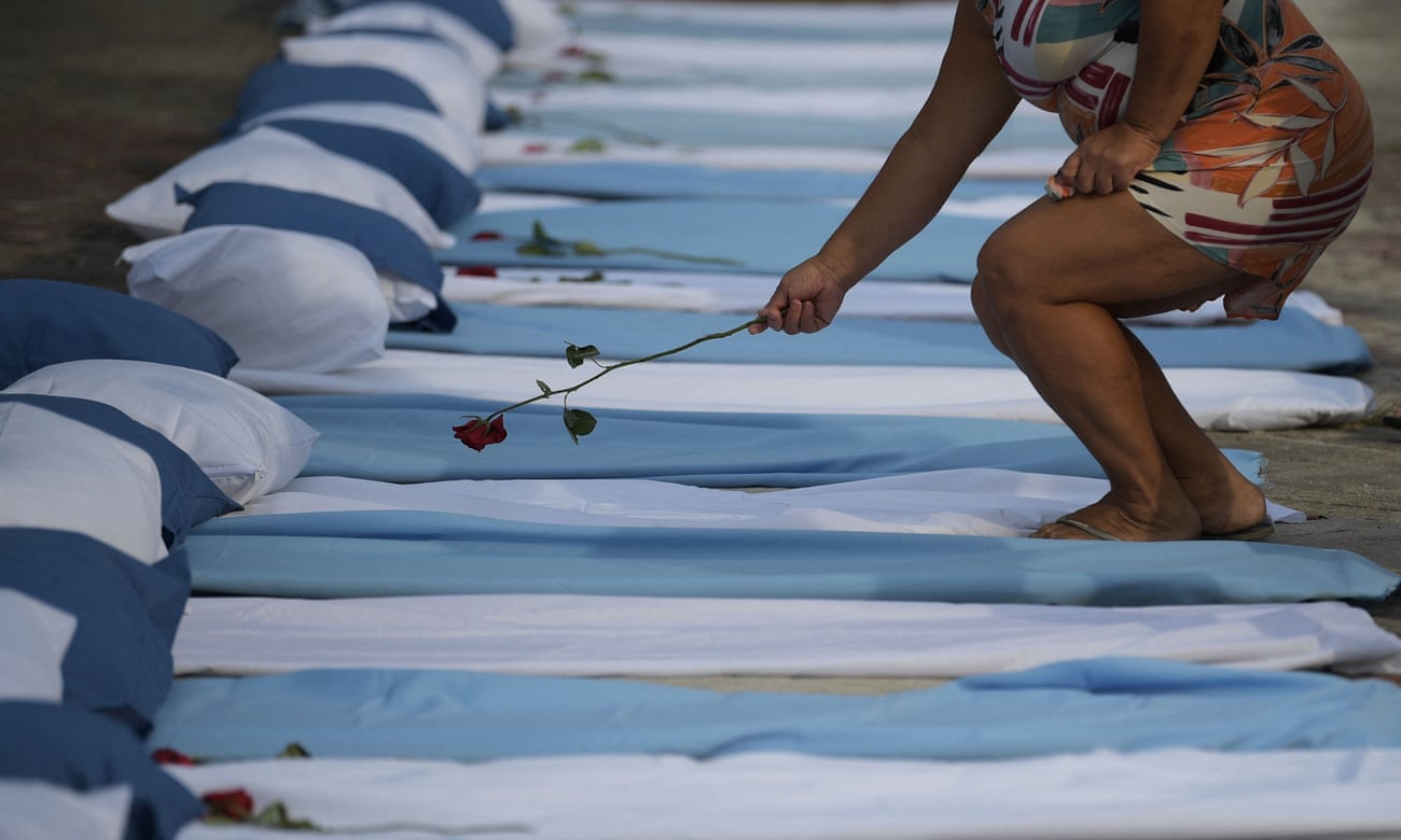 A woman lays a rose on mattresses symbolising coronavirus victims at a protest in Rio against Brazilian president Jair Bolsonaro’s pandemic response 