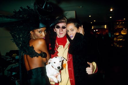 Naomi Campbell in black feathers, Philip Treacy with a white dog and Christy Turlington in black hugging each other