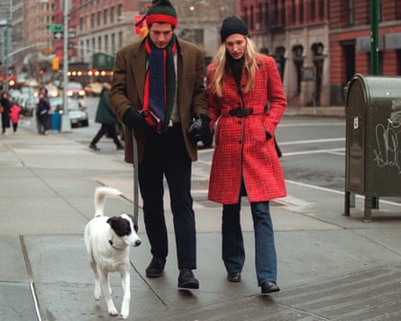 Kennedy Jr and Bessette Kennedy wearing hats, coats and jeans, walking with a dog