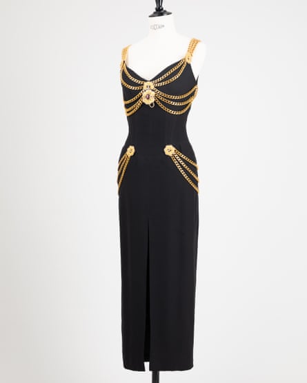 long black sleeveless crepe dress with gold chains draped around the waist, over the shoulders as straps, and around the waist