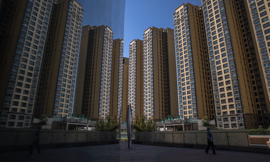 A woman walks through Evergrande city plaza, next to its apartment buildings in Beijing.