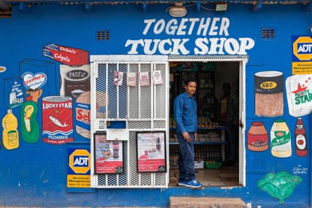 man stands in the doorway of his brightly painted shop