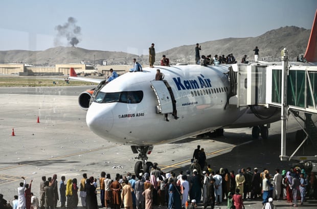 Afghan people climb atop a plane at Kabul airport in August 2021