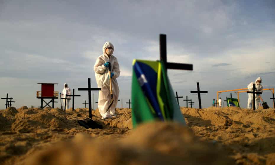 Activists wearing protective gear dig graves on Copacabana beach to symbolize those who died of coronavirus in Rio de Janeiro, Brazil, on 11 June. 