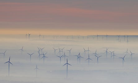 Wind turbines shrouded in fog near Petersberg mountain, Germany.
