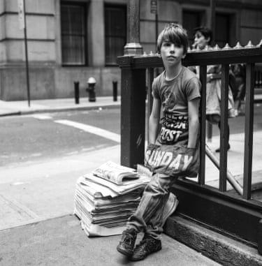 a young boy next to newspapers