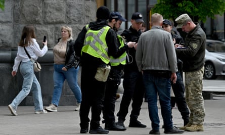 A Ukrainian serviceman and police officers check the documents of a man in the centre of Kyiv