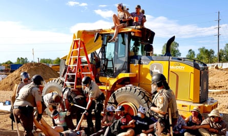 Police arrest protesters who have climbed on top of an earth mover.