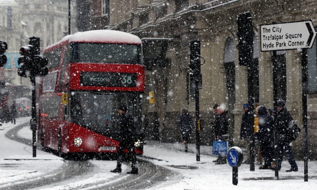 People walk in the street during a heavy snow in London.