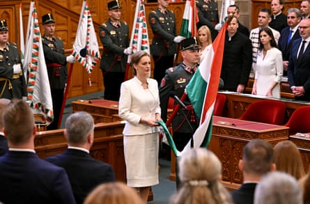 Ágnes Forsthoffer holds a corner of the Hungarian flag while standing before parliament