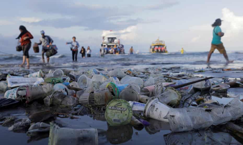 Tourists and local residents disembark a boat amid plastic rubbish in Sanur, Bali