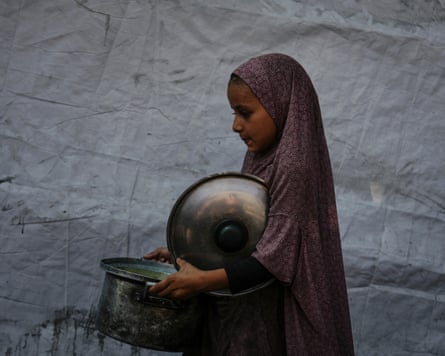 A girl carrying pan filled with donated food
