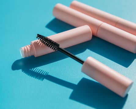 A mascara wand on a plain blue background