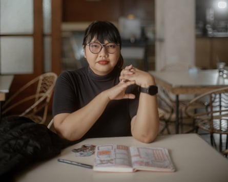 Lina Meilina, an Illustrator in Bandung, Indonesia, sitting at a table with a notebook in front of her