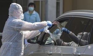 A doctor collects a coronavirus test from a car driver at a test centre on the grounds of a school in Fürstenwalde, Germany