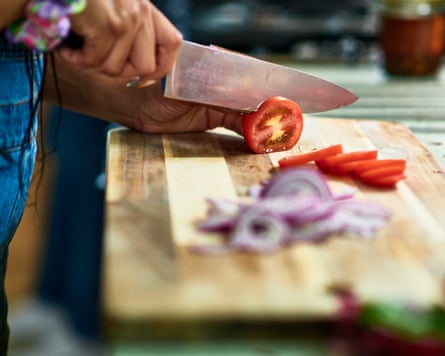 A woman chopping tomatoes on a wooden board
