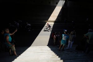 Spectators take photos of the riders as they pass through a shaft of light.