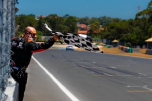 A man beside a motor racing track waves a checkered flag