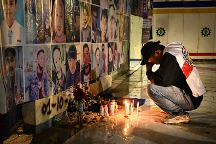 A man mourns in front of a memorial to victims of the 2022 stampede at the Kanjuruhan stadium that killed 135 people