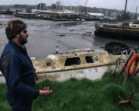 Green stands next to a boat with no windows which is covered in algae.