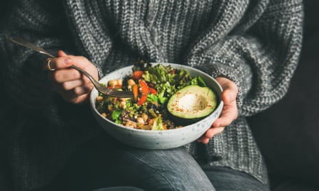 Woman in a thick jumper eating fresh salad, avocado, beans and vegetables