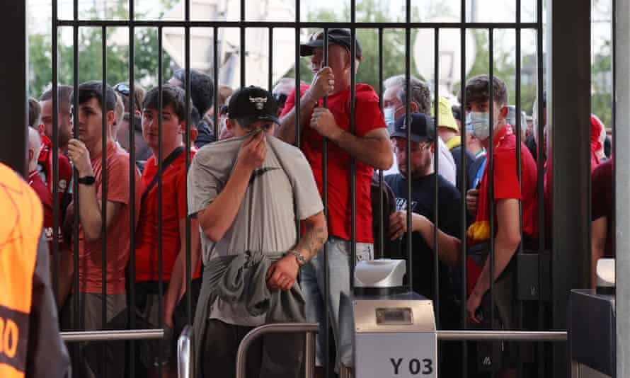 A Liverpool feeling the effects of tear gas enters the Paris stadium as many others queue outside.