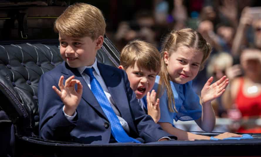 Prince George, Prince Louis and Princess Charlotte wave as they ride in an open carriage on the Mall.