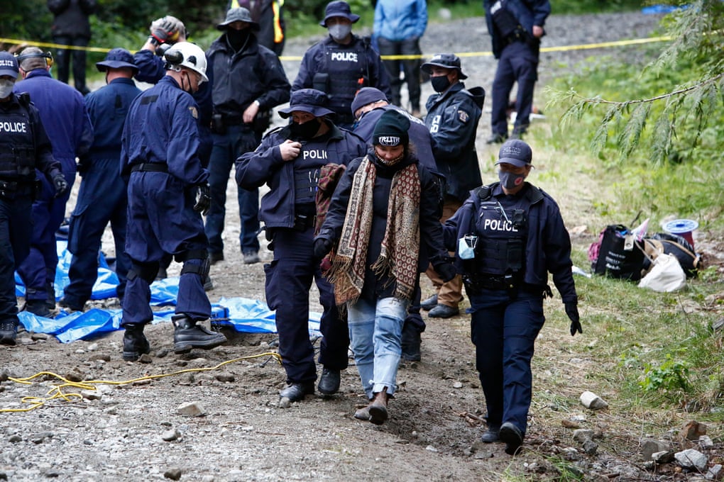 Police escort a protester away after their arrest for blocking a logging road on southern Vancouver Island, in British Columbia, Canada.
